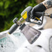Active pressure washer swivel gun with soap tank held by a person wearing black gloves, with a blurred outdoor background.