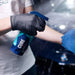 Person applying a product labeled 'GYEON CURE' to a car with a blue towel.