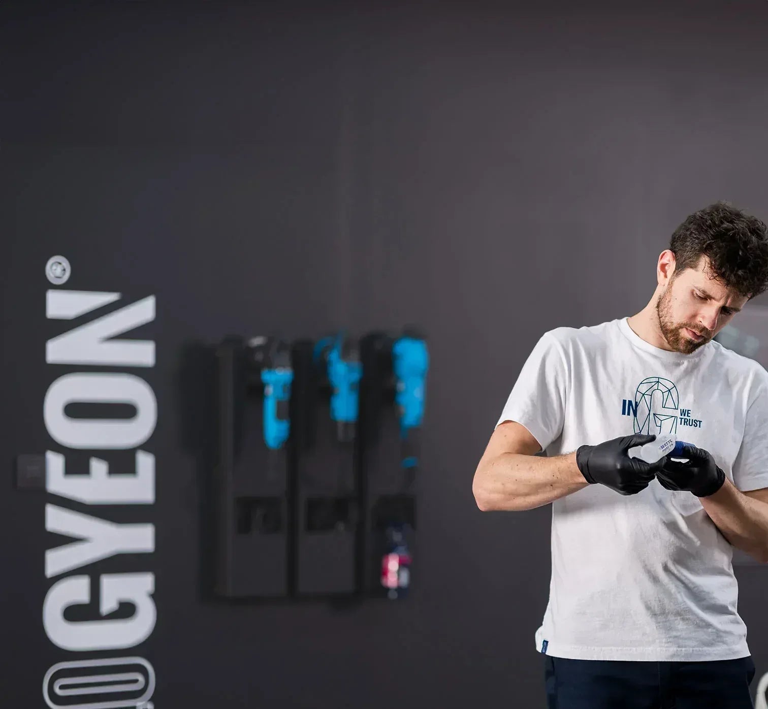 Man preparing for a workout with gloves on, standing against a dark background with 'GYEON' branding.