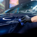 Person cleaning a car window with a blue cloth in a car wash setting