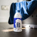 Bottle of GYEON towel wash with a blue cap on a wooden surface, with a blue towel in the background.