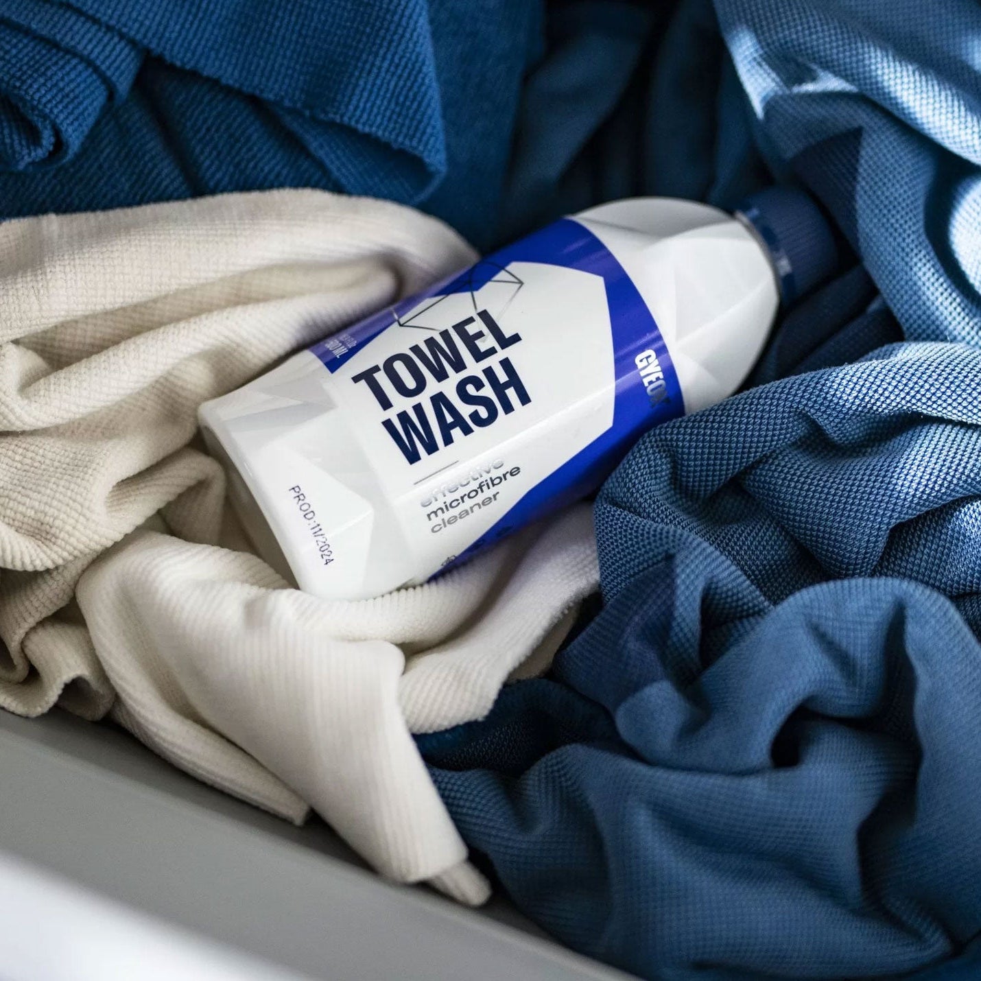 Bottle of GYEON towel wash surrounded by folded towels in a basket