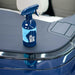 Blue spray bottle labeled 'Gyeon Water Spot Remover' on a car's black dashboard.