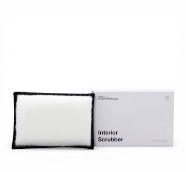 A white plush interior scrubber with a black fuzzy trim, shown next to its white packaging box labeled 'Interior Scrubber' by Bath Body Works.