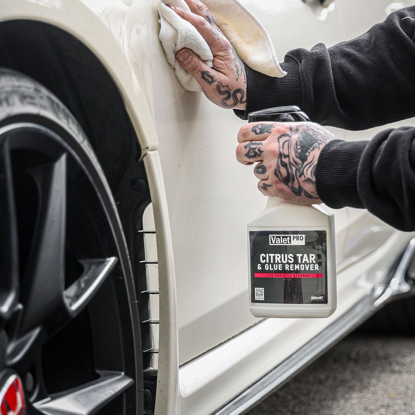 Person cleaning a car door with a bottle of Valet Pro Citrus Tar & Glue Remover.